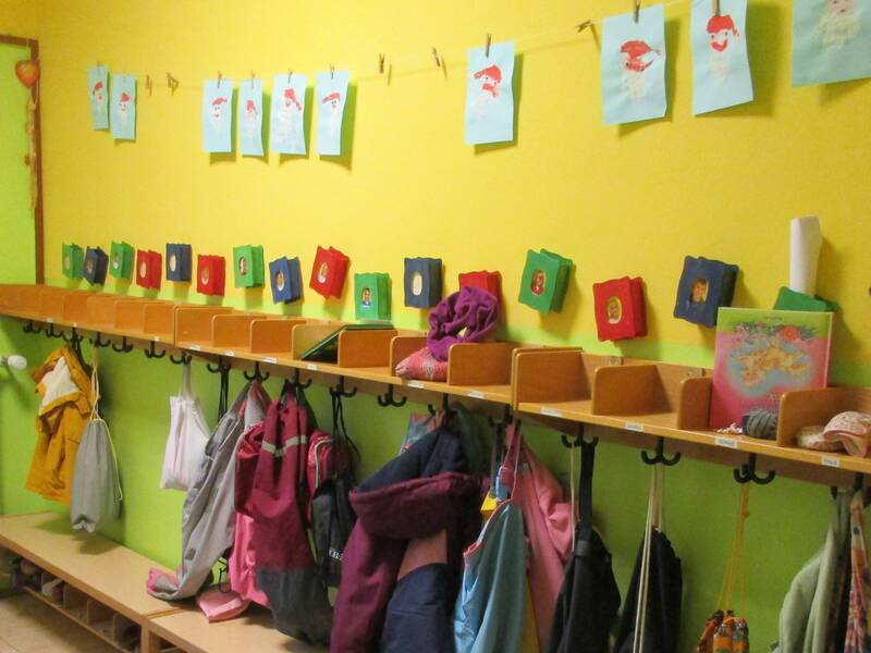 Kindergartengadarobe, Ablagefächer und Kleiderhacken vor einer grünen und gelben Wand